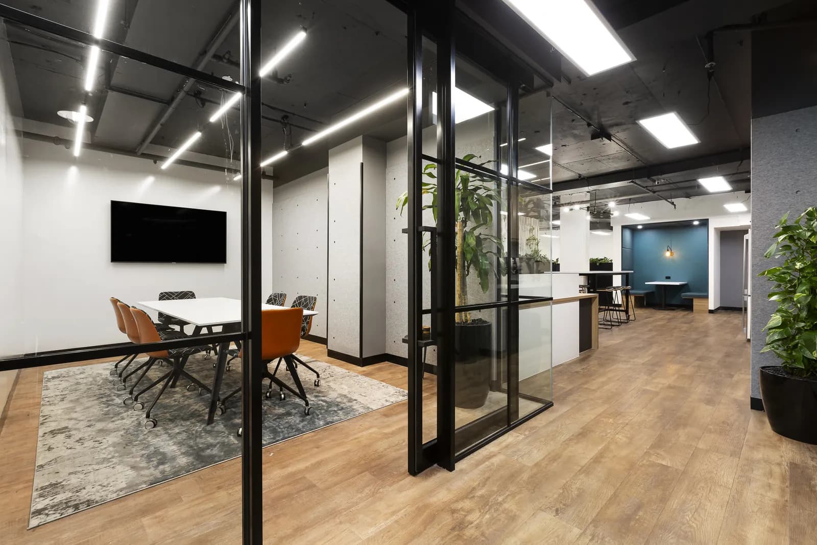 Modern commercial office interior with glass meeting rooms and warm timber finishes